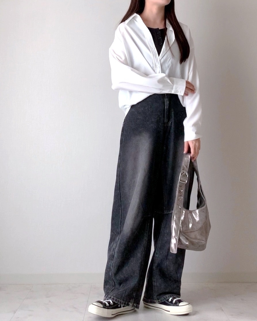 女性が白いシャツとデニムのロングスカートを着用し、シルバーのバッグを持っています。カジュアルでシックな装いです。
