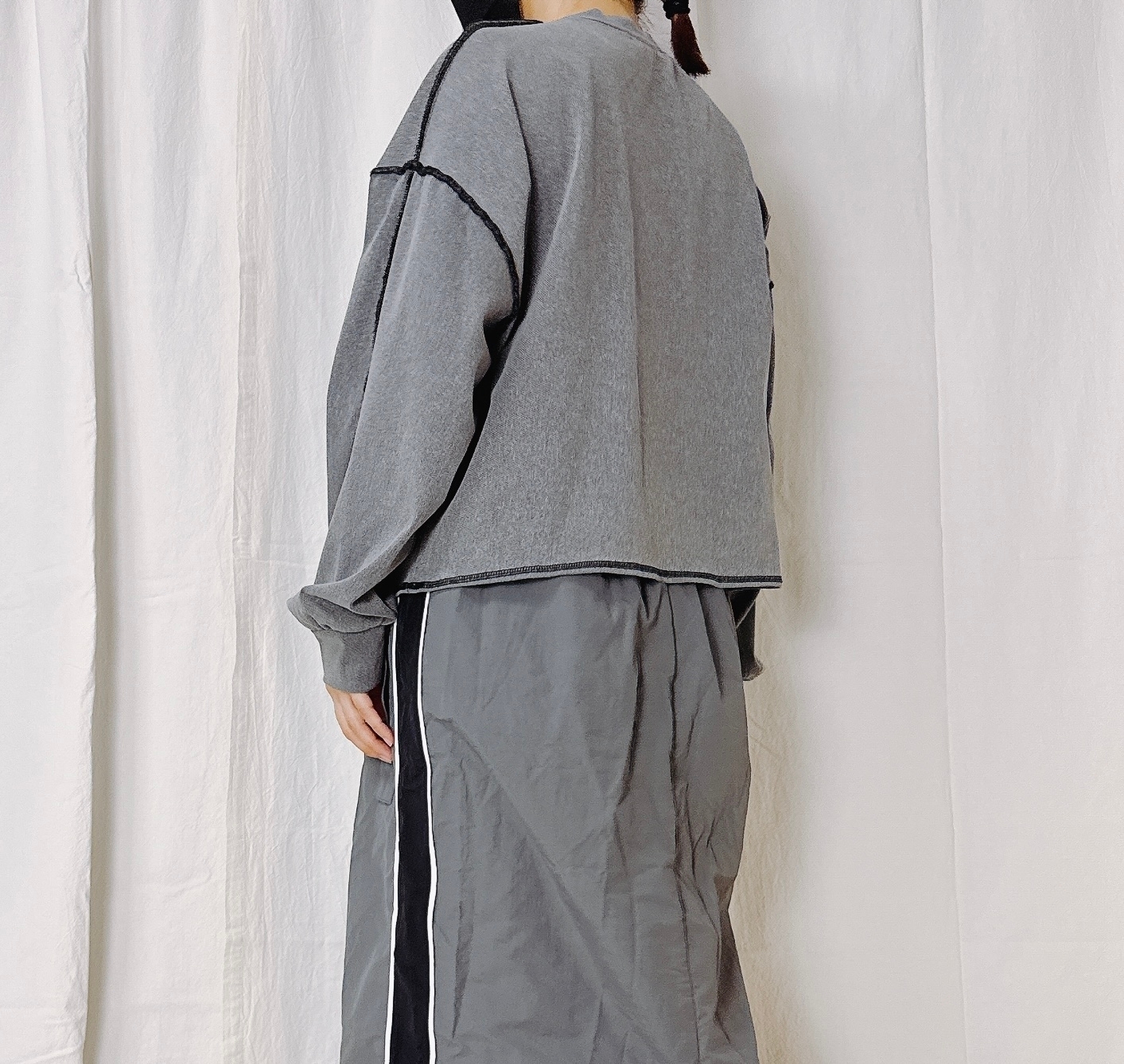 人物がゆったりとしたカジュアルな服装を着て後ろ向きに立っている。