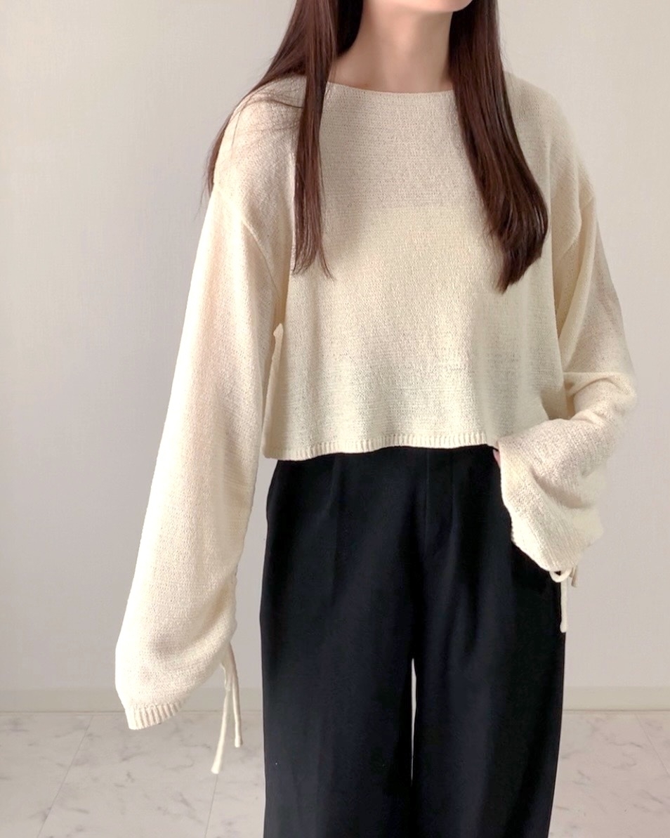 女性が長袖のニットとワイドパンツを着ています。