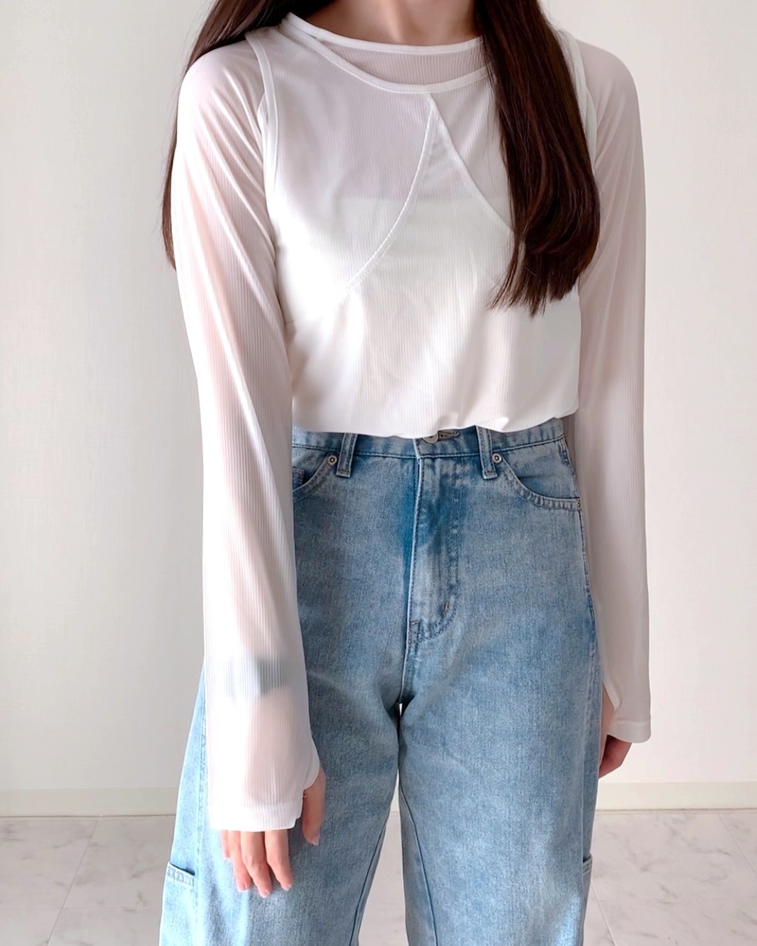 女性がシンプルな白いトップスとジーンズを着ているファッションスナップ。