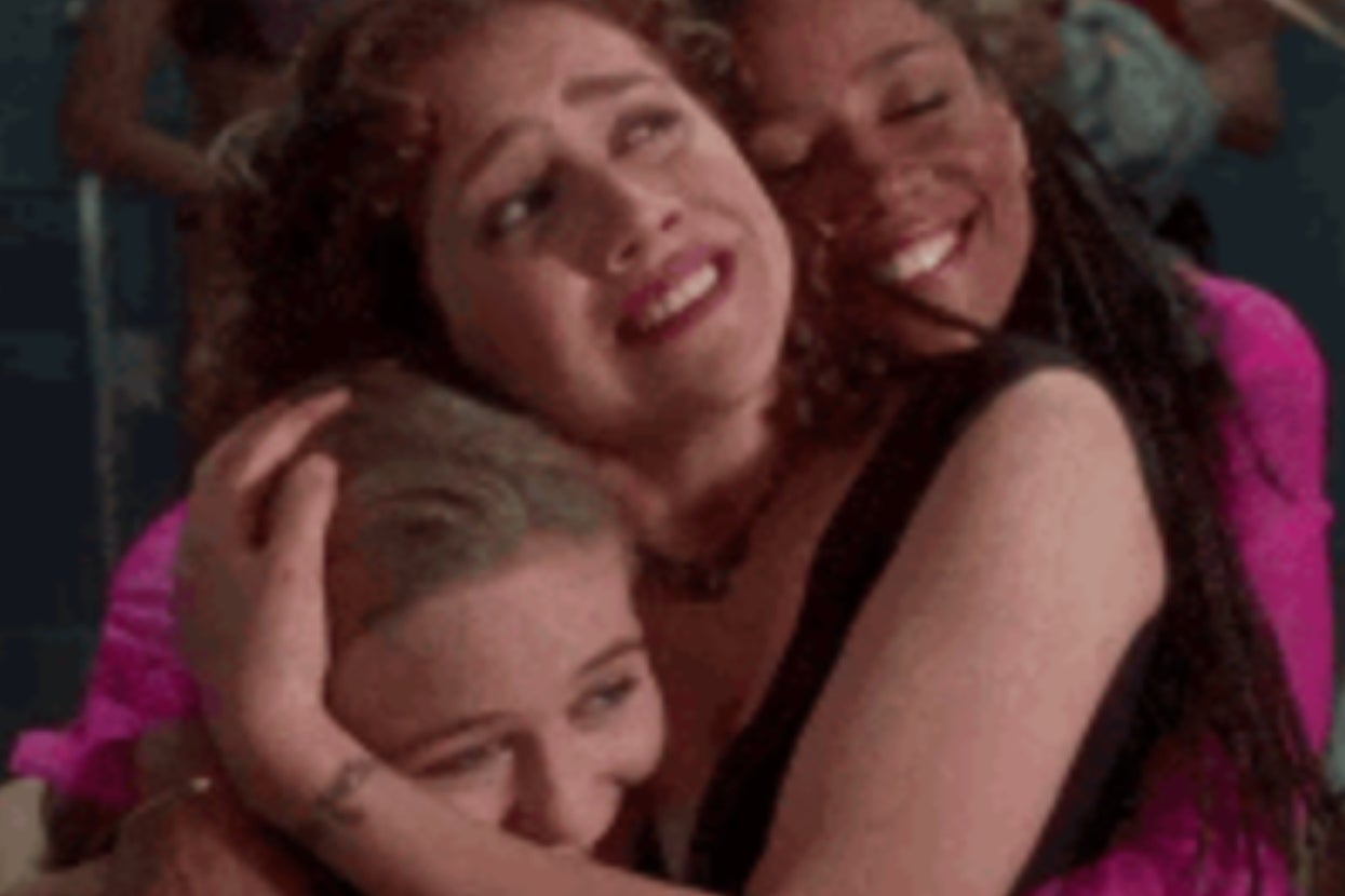 Three people smiling and embracing joyfully in a group hug, conveying a sense of camaraderie and happiness