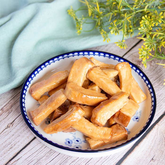 プレートに盛られた食パンを使ったお菓子が、木製のテーブルに置かれている。緑の植物が背景にある。