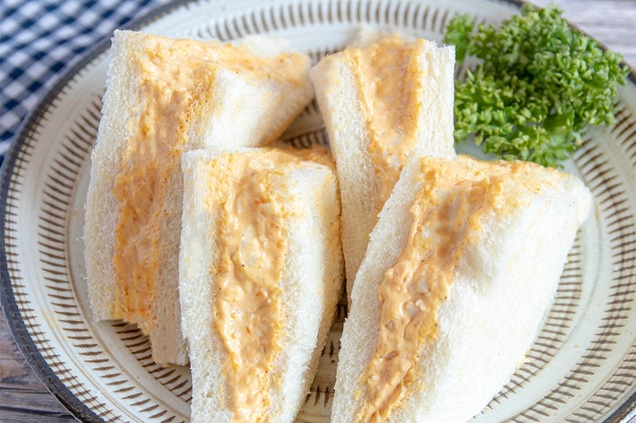 お皿に盛られたサンドイッチ。クリーミーなフィリングが挟まれており、緑のパセリが添えられています。