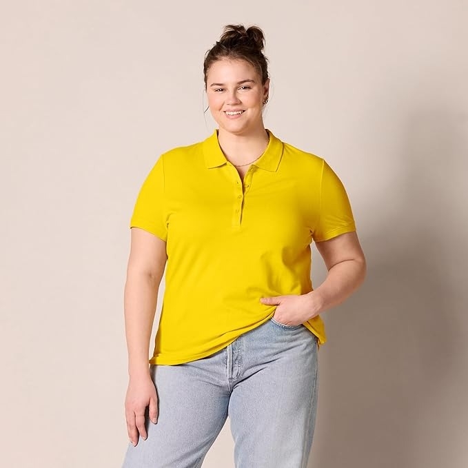 Person in a casual yellow polo shirt and light jeans standing with a relaxed pose and slight smile