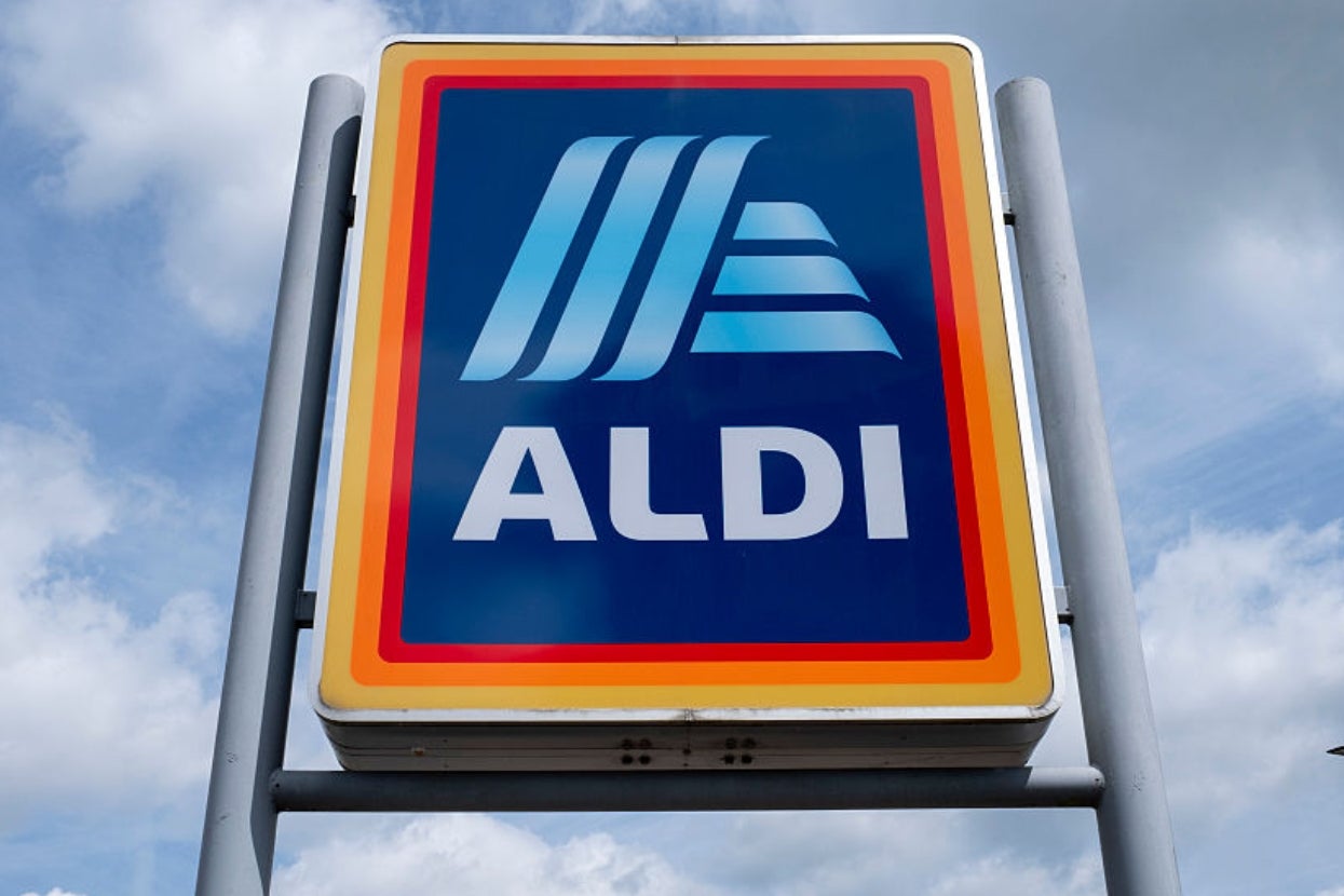 Aldi supermarket sign against a cloudy sky, featuring the store's iconic logo and name