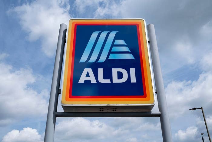 Sign of an Aldi supermarket against a cloudy sky, featuring the bluish and achromatic Aldi logo