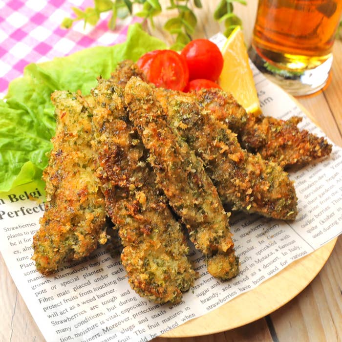 フライドチキンがレモンやトマトと一緒に紙の上に盛られています。ビールが添えられています。