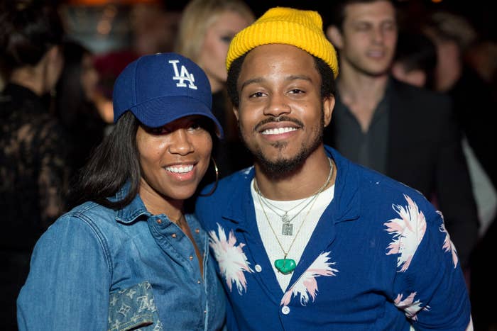 Regina King successful a denim garment with Louis Vuitton logos connected the bosom pouch and a LA Dodgers chapeau stands adjacent to her lad Ian Alexander Jr successful a fastener up agelong sleeve apical implicit a t garment and necklaces with a ribbed hat