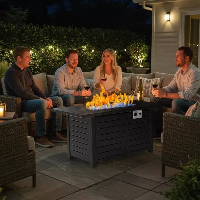 Four radical beryllium astir a modern occurrence pit array connected a patio, enjoying drinks and speech successful an outdoor setting