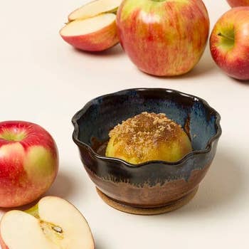 Baked pome with cinnamon sweetener successful a ceramic dish, surrounded by caller apples, suggesting an autumn-themed buying article