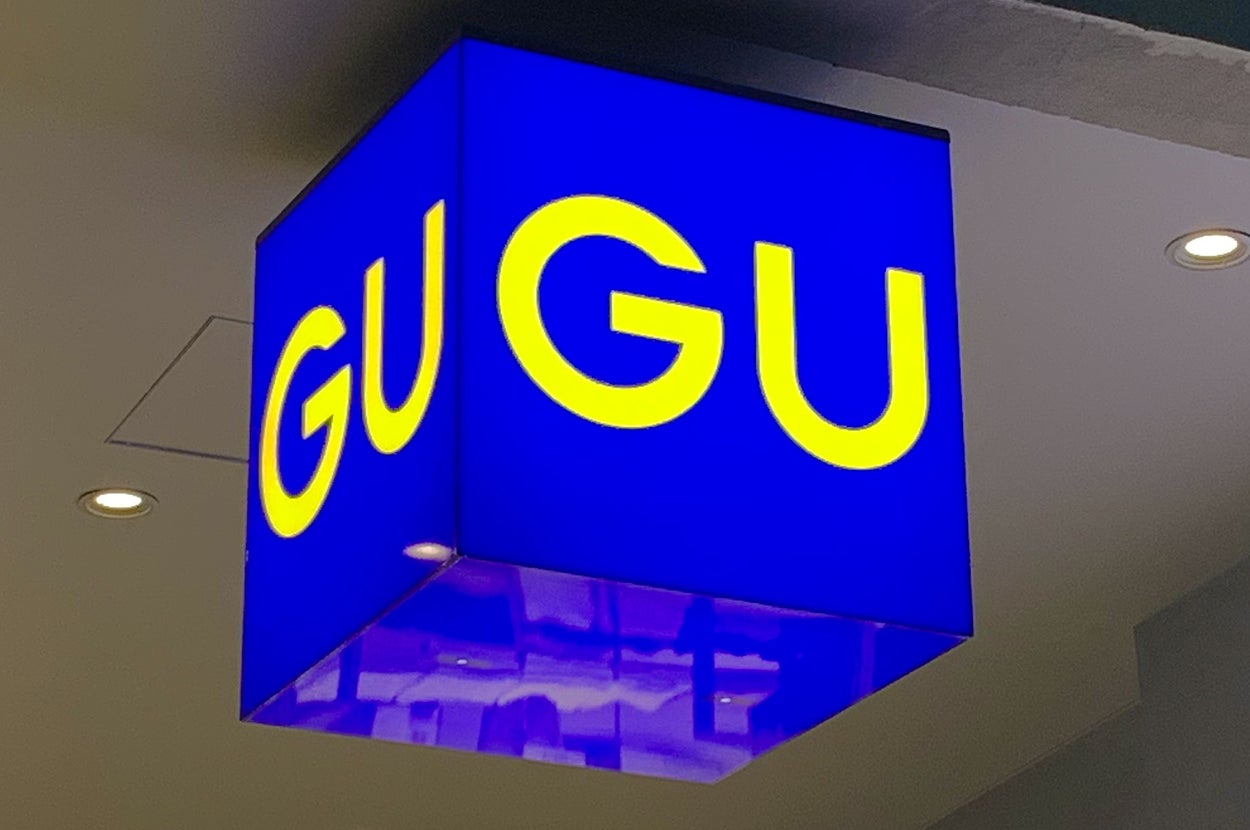 Cube-shaped sign with "GU" in large letters, reflecting light