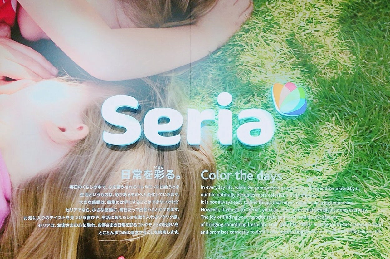 Seriaの広告画像。芝生に横たわる2人の子供に「日常を彩る。」のコピーが添えられている。