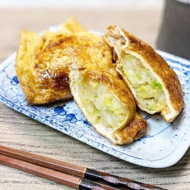 皿に載った焼き揚げの袋が割れて中のキャベツが見えている料理。タネが詰まった和風食品。