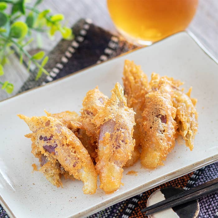 白い皿に盛られた天ぷら料理。背後には緑の植物と飲み物が見える。