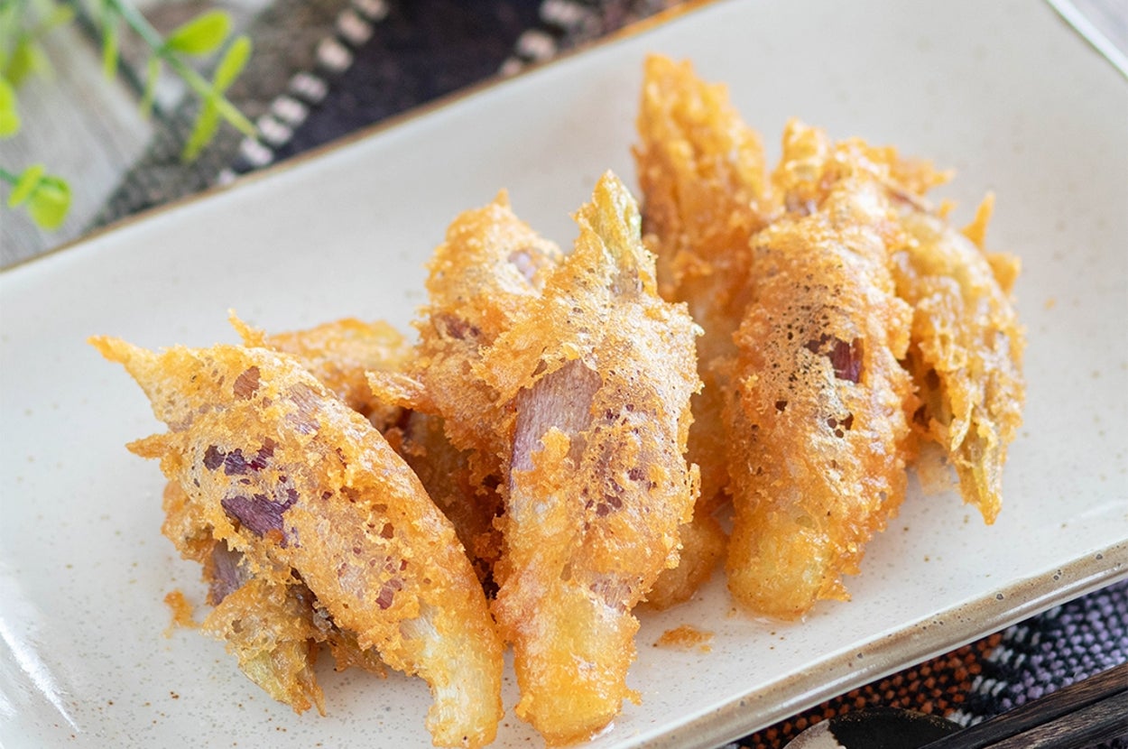 皿に盛られた揚げ餃子。サクサクの衣と具材が見える。背景に飲み物と植物が少し写っている。