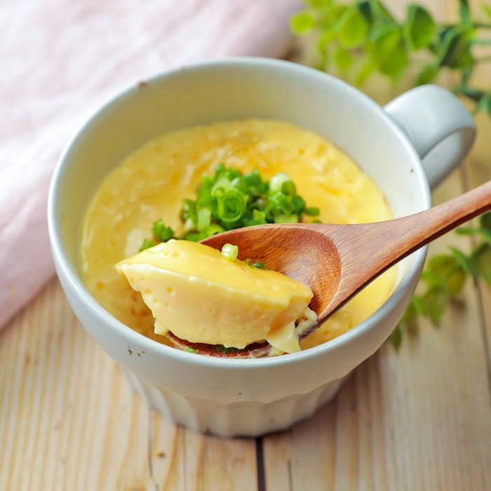 カップに入った茶碗蒸しをスプーンですくった様子。トッピングにネギが少々載っている。