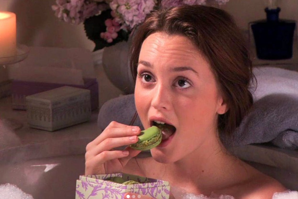 Blair Waldorf from "Gossip Girl" in a luxurious bath, eating a macaron, surrounded by candles and flowers