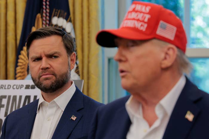 Two men are successful a country speaking; 1 wears a suit, and the different wears a "USA" chapeau and suit. An American emblem is partially disposable successful the background