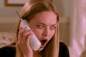 Person with long hair, holding a retro phone, looks surprised with mouth open wide