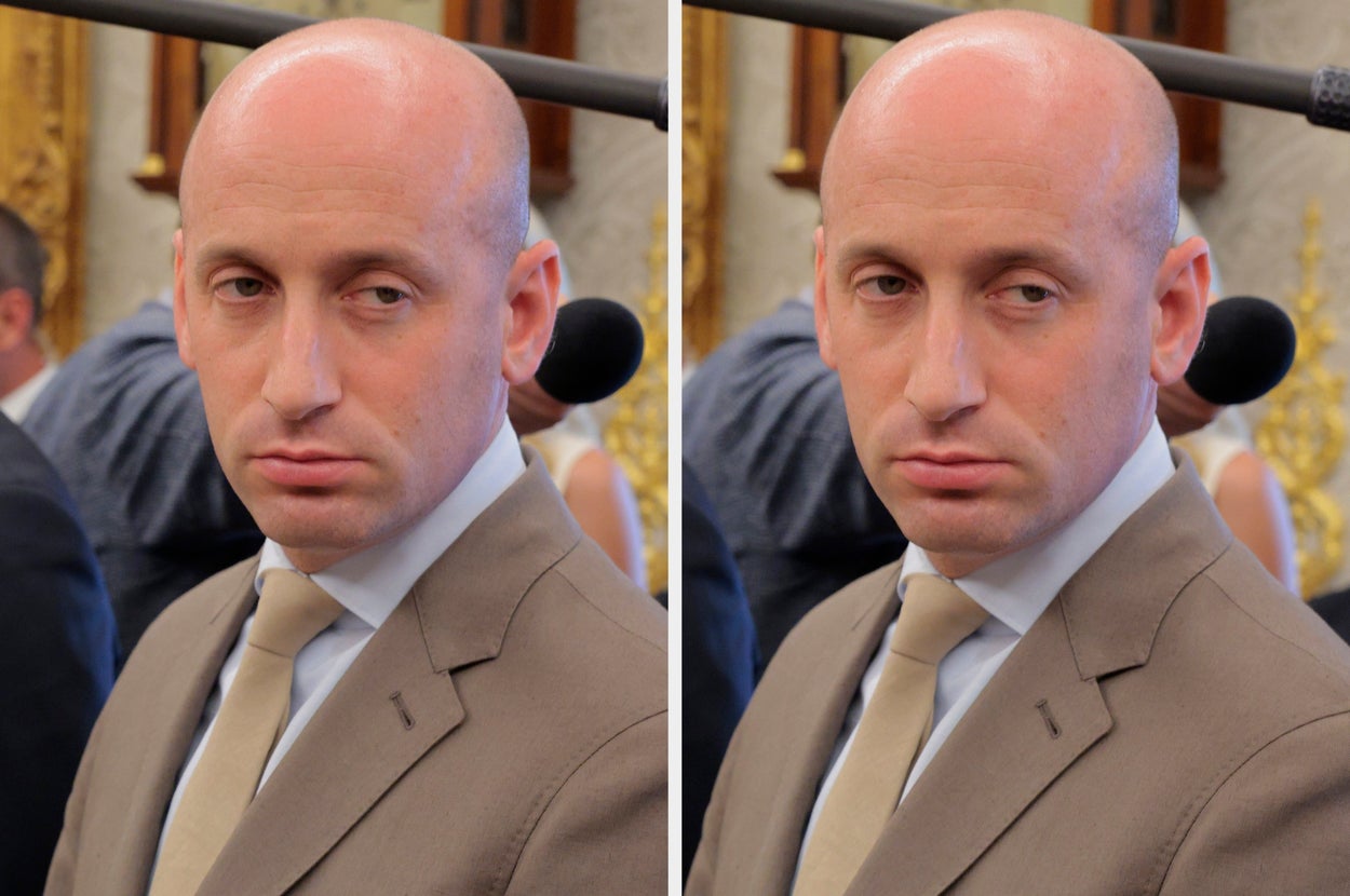 A person in a suit and tie looks into the distance with a neutral expression while at an event