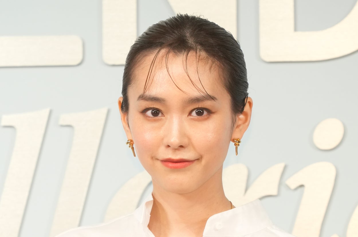 画像の女性は、ゆったりしたシャツとパンツを着て、小さなバッグを持っています。
