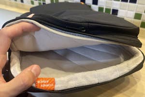 ノートパソコン用スリーブの開いた状態を見せる手。柔らかい内側が見える。