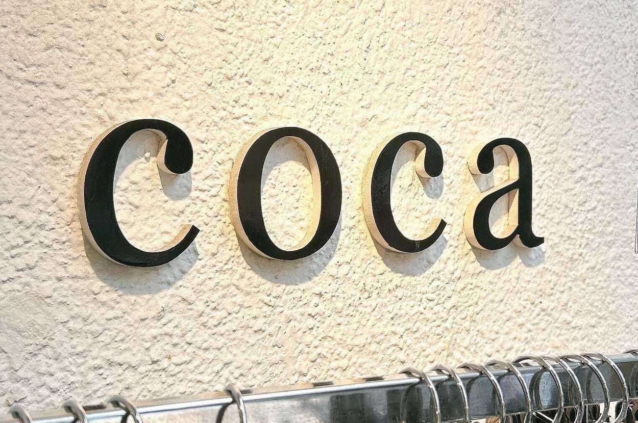衣類のラックに「coca」のロゴが壁に表示されている店内の様子。
