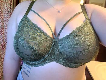 Person wearing a greenish lace bra with delicate floral patterns, showcasing lingerie style