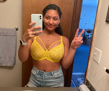 Person successful a reflector selfie wearing a lace bralette and denim shorts, making a bid sign