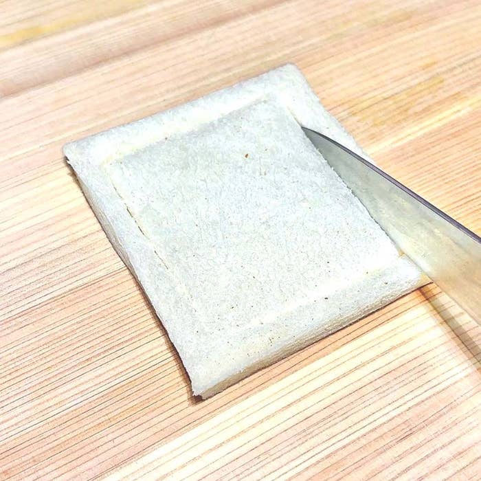 食パンの縁を包丁で切り落としている様子。