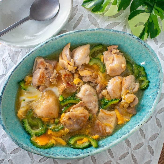 皿に盛られた鶏肉とゴーヤの炒め物。スープ状で、隣にスプーンと皿がある。