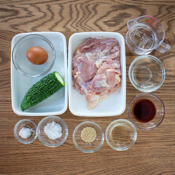 食材が並ぶ調理台。鶏肉、卵、ゴーヤ、調味料が透明の器に入っている。