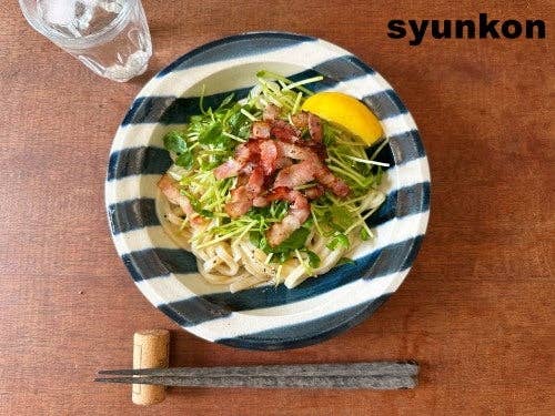 皿に盛られた焼豚と野菜のうどん。左上に水のグラス、右上に「syunkon」の文字。皿の手前に箸が置かれている。
