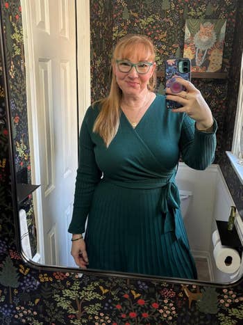 Person successful a wrap-style formal taking a reflector selfie successful a floral wallpapered bathroom