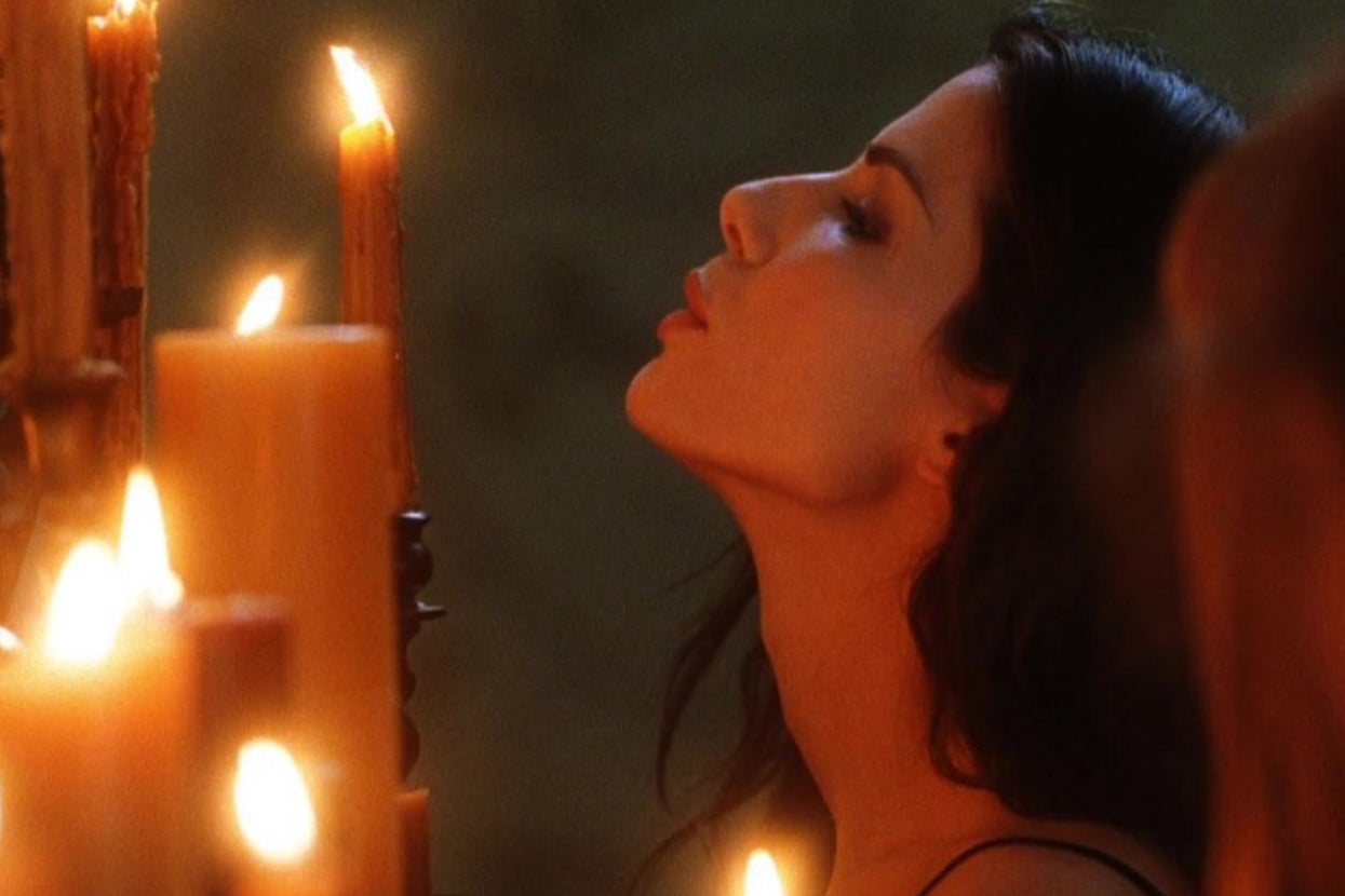 Person leaning close to several lit candles, appearing contemplative