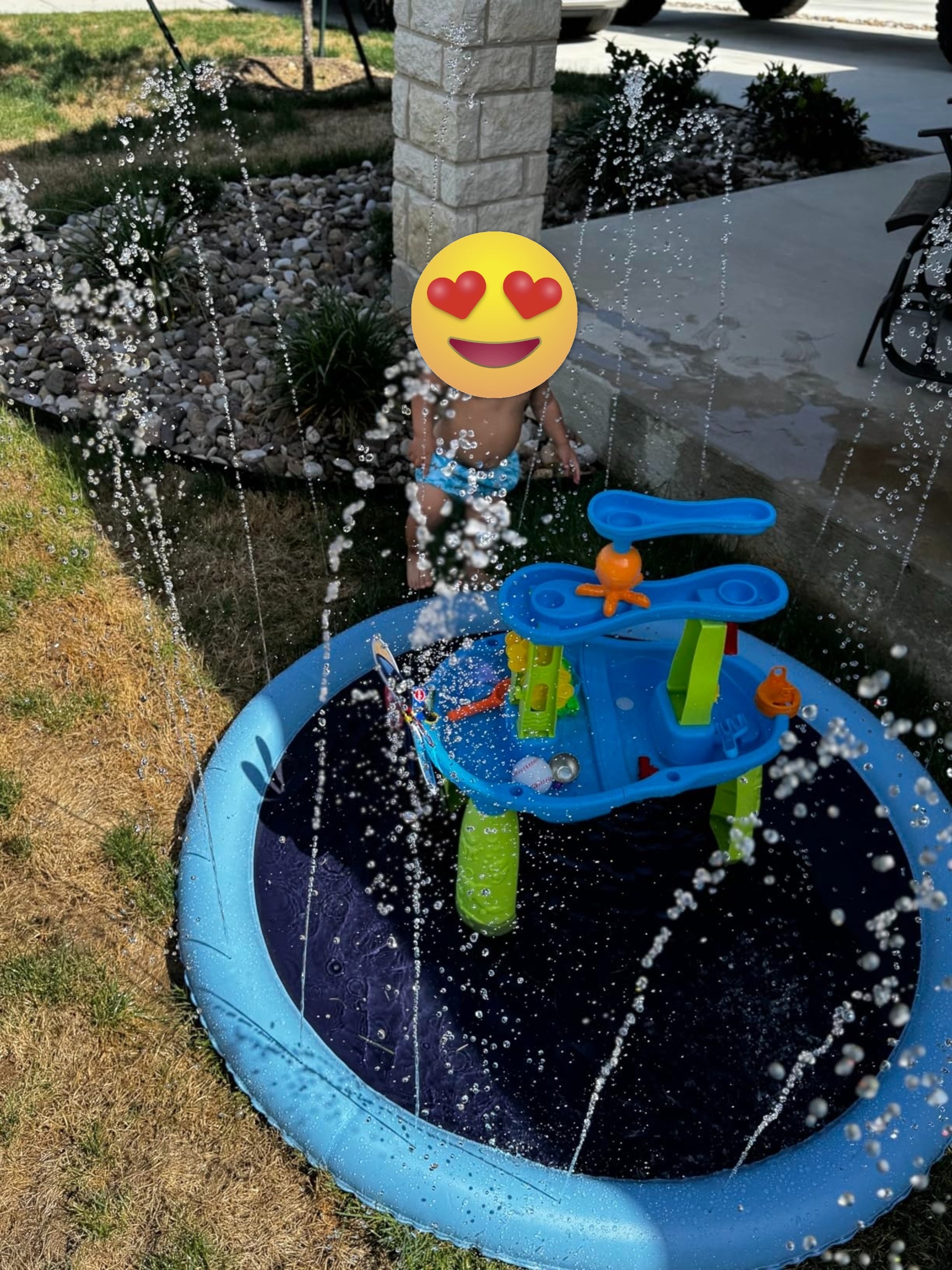 Toddler playing successful  a backyard splash pad with h2o  jets spraying. The artifact  array  has interactive features for h2o  play. Cozy outdoor setting