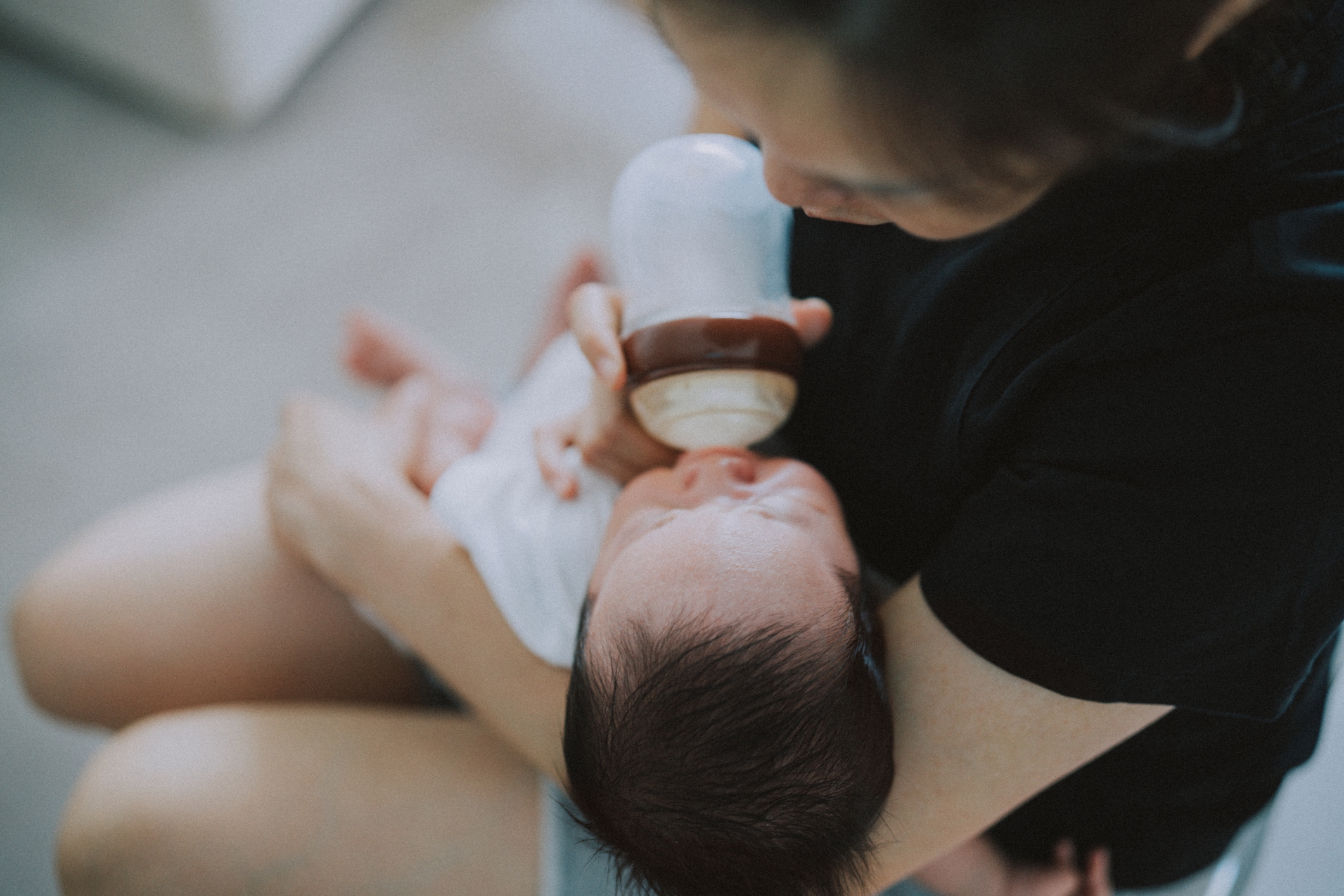 En person mater en baby med en flaske, vugger dem forsiktig i armene