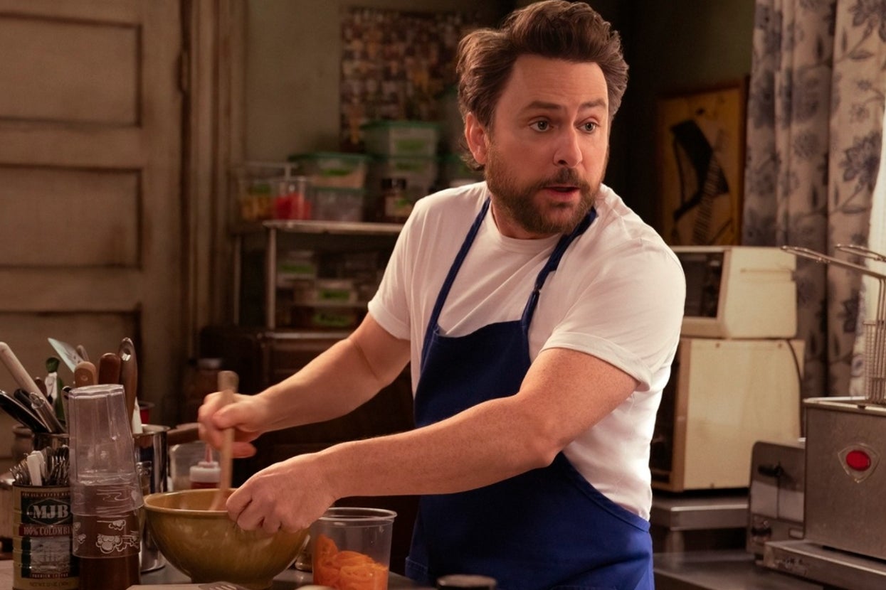 Person in a kitchen, wearing a blue apron and stirring ingredients in a bowl, cooking or preparing food