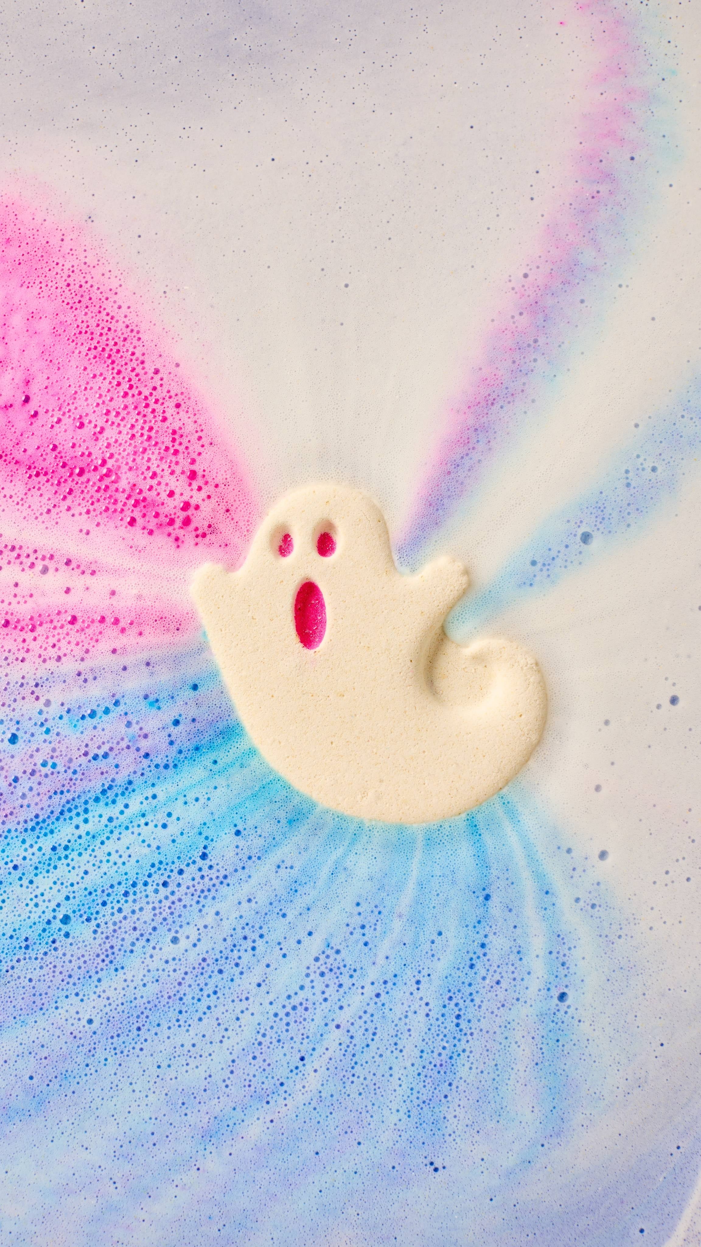 Ghost-shaped bath bomb dissolving with colorful swirls of blue and pink around it