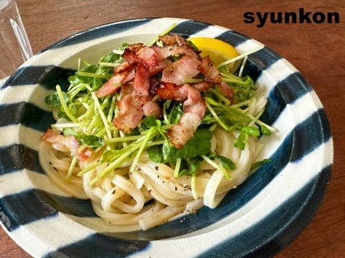パスタの上にベーコンとクレソンが乗った料理。