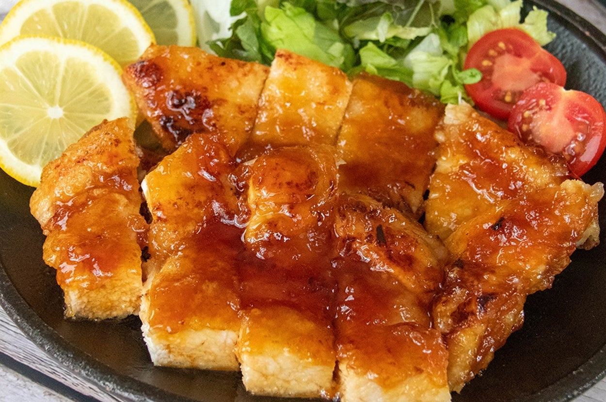 レモンスライス、サラダ、トマトを添えた鶏むね肉のはちみつレモンチキンの料理。