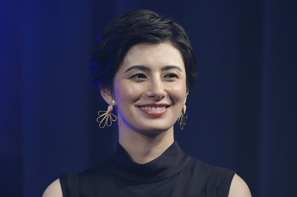 ショートカットの女性が幾何学模様のドレスを着てイベントで笑顔。