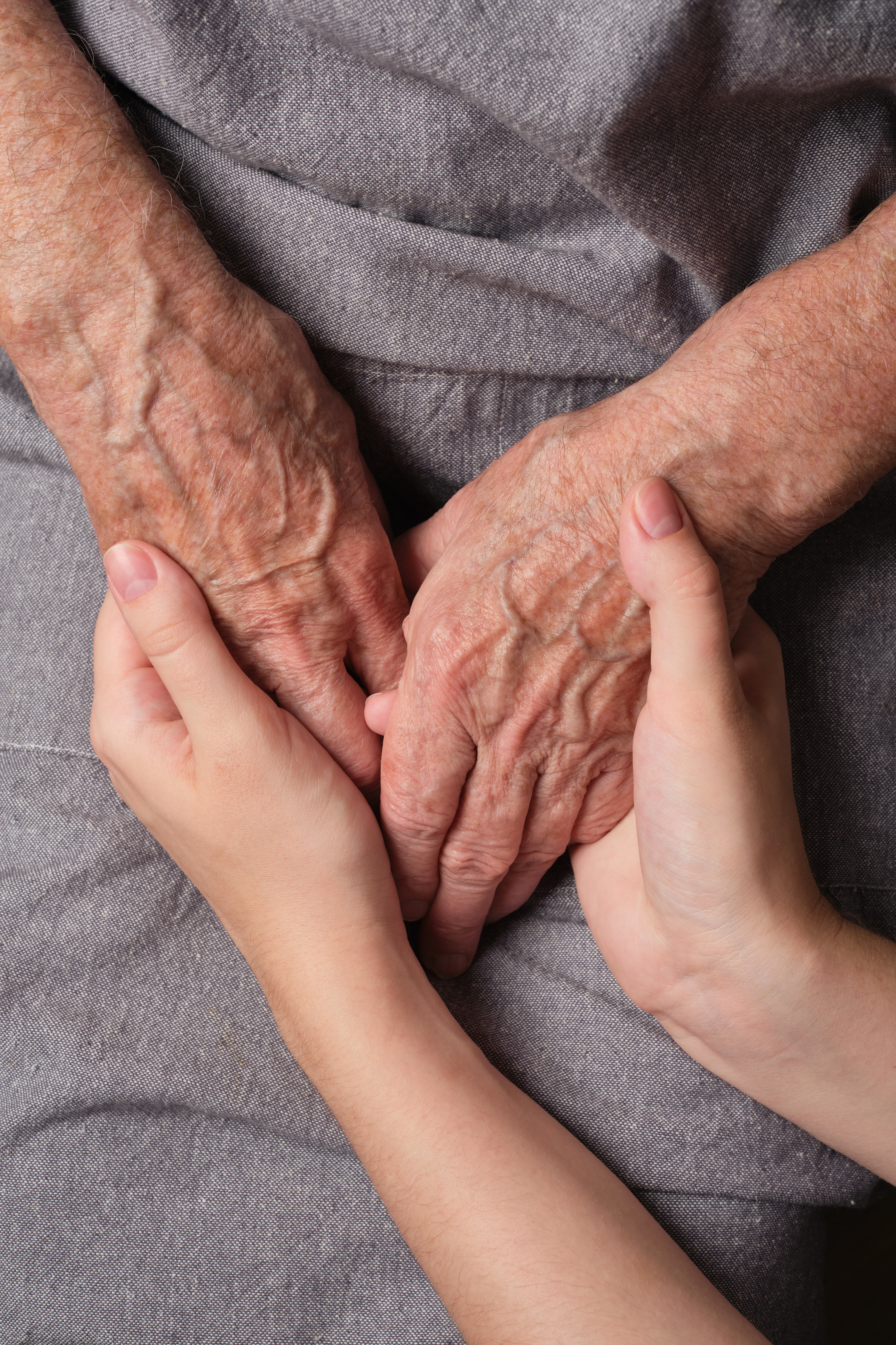 Unge hender holder forsiktig og støtter eldre hender, formidler omsorg og forbindelse