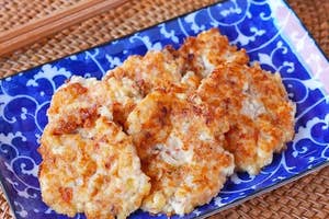 青い模様の皿に載った数枚の揚げ物料理。添えられた醤油の小皿と箸が横にある。