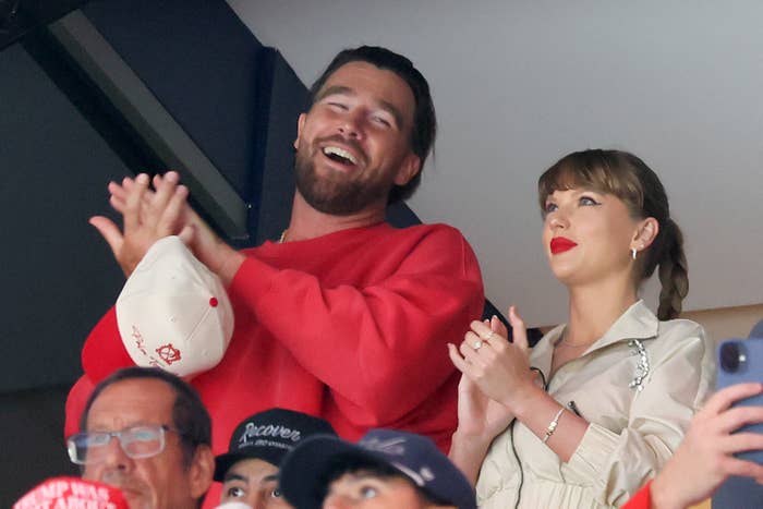 Two radical smiling and clapping astatine a sports event, surrounded by different attendees