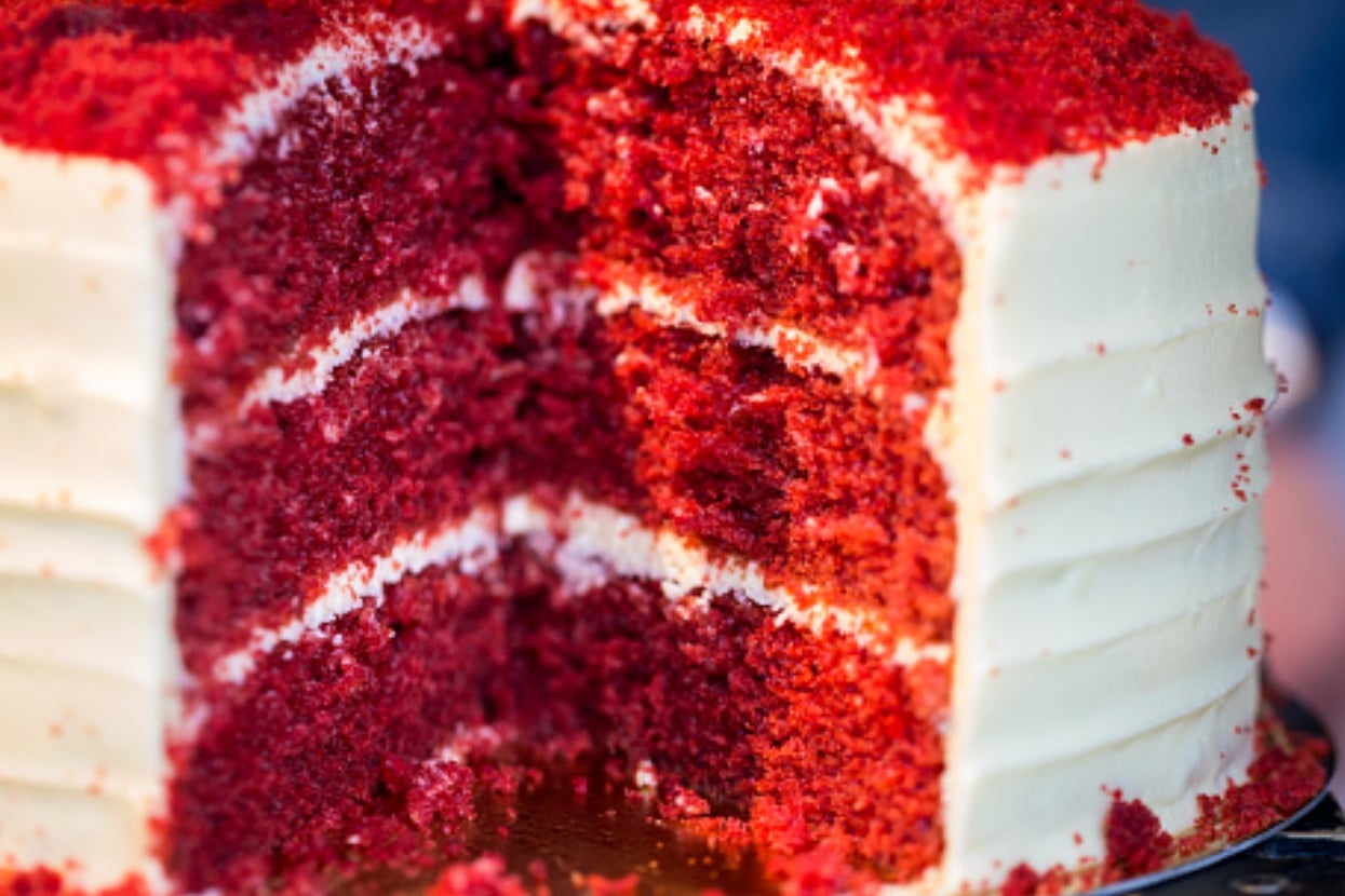 A close-up of a sliced layered cake with textured red interior and smooth white icing on the outside