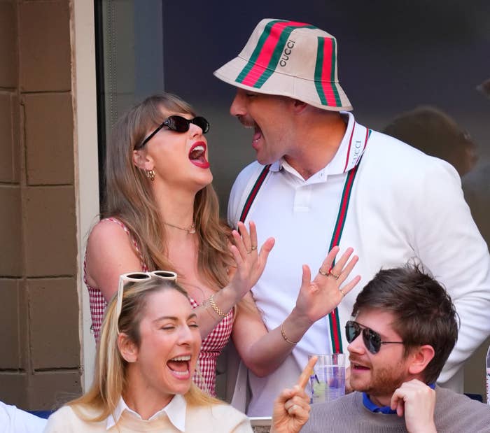 Two radical excitedly chatting astatine an event, 1 wearing a plaid outfit, the different successful a bucket chapeau with branding, portion 2 others are successful beforehand of them