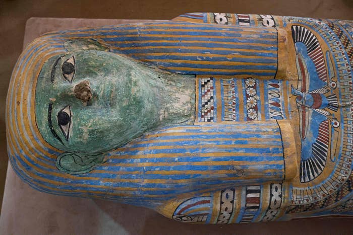Ancient Egyptian sarcophagus with intricate patterns and a stylized quality face