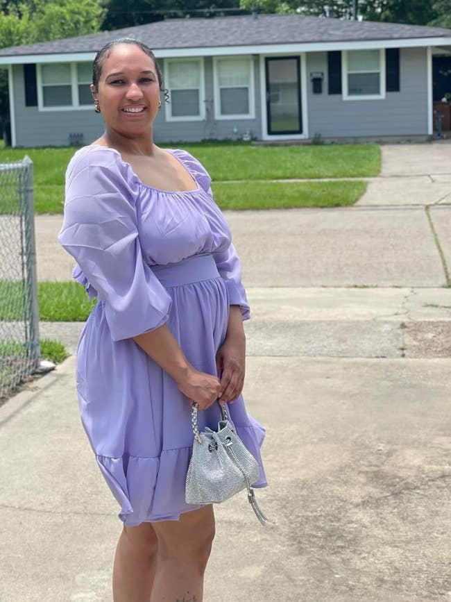 Person smiling outdoors successful a ruffled formal holding a sparkly purse, lasting successful a driveway with a location successful the background