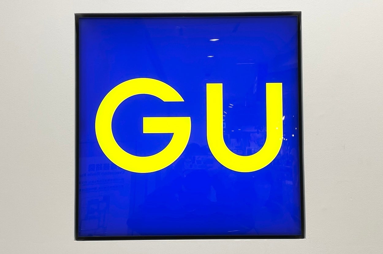 A square sign displaying the letters "GU" in a bold, modern font